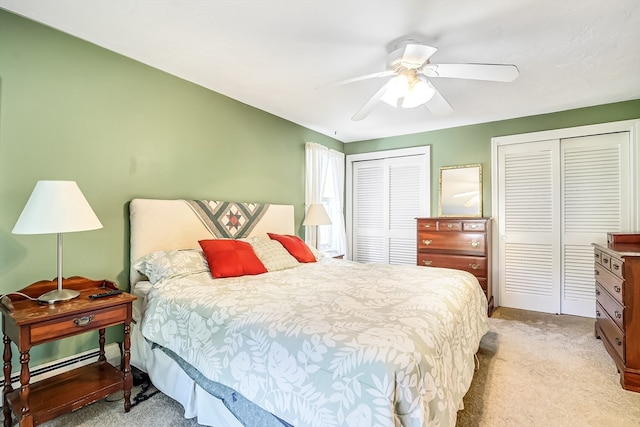 carpeted bedroom with ceiling fan and two closets