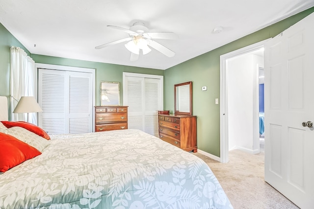 carpeted bedroom featuring ceiling fan and multiple closets