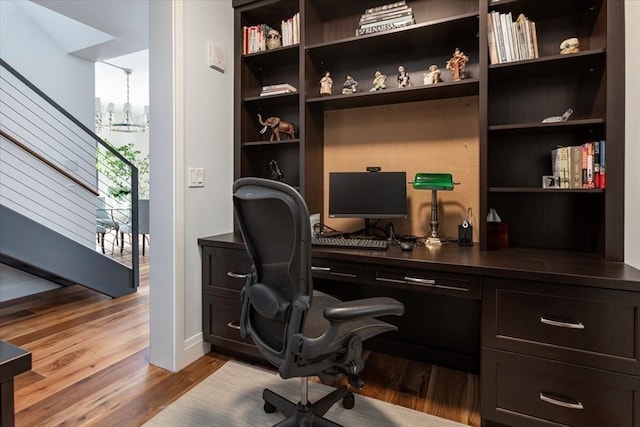 home office with a chandelier and light hardwood / wood-style flooring