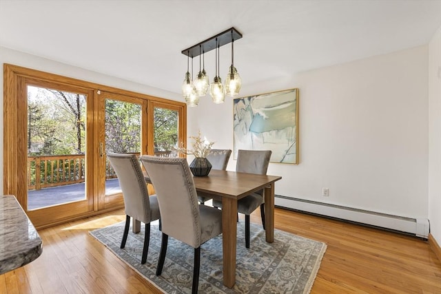 dining room featuring light wood-style floors, a chandelier, baseboards, and a baseboard radiator