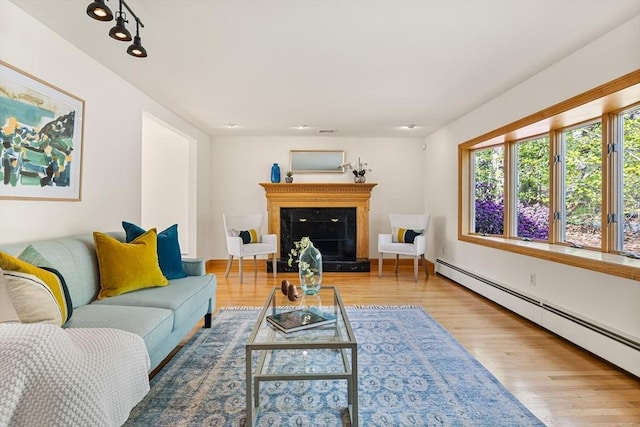 living area with a fireplace with raised hearth, wood finished floors, and baseboard heating