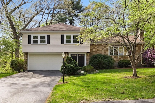 tri-level home featuring an attached garage, driveway, and a front yard