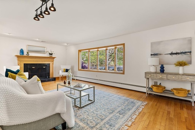 living room featuring wood finished floors, a fireplace with raised hearth, and a baseboard heating unit