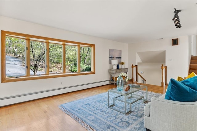 living area with track lighting, a baseboard radiator, and wood finished floors
