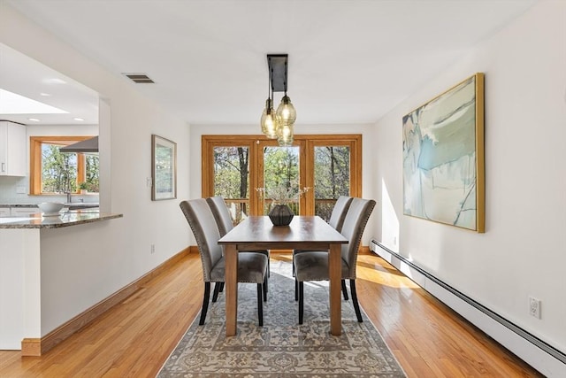 dining area featuring visible vents, a baseboard heating unit, a wealth of natural light, and light wood-type flooring
