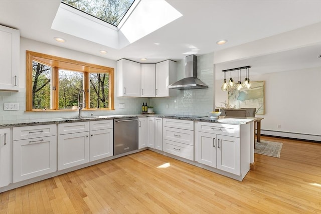 kitchen with wall chimney range hood, dishwasher, a sink, a baseboard heating unit, and light wood finished floors