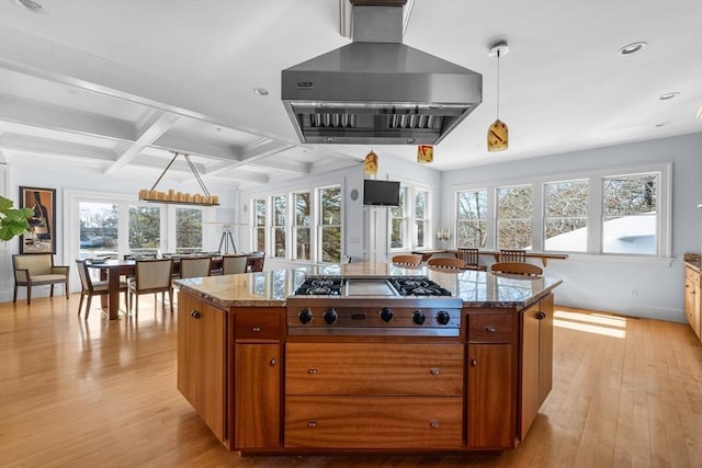 kitchen featuring hanging light fixtures, range hood, stainless steel gas stovetop, and brown cabinetry