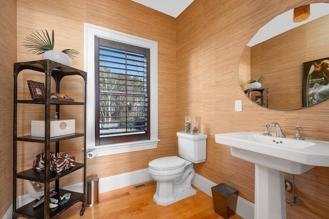 bathroom with toilet, a skylight, baseboards, and wood finished floors