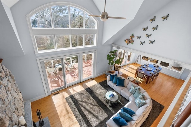 living area featuring a ceiling fan, baseboards, high vaulted ceiling, and wood finished floors