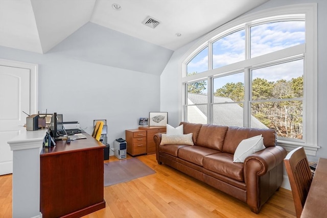 home office with light wood-style floors, lofted ceiling, and visible vents