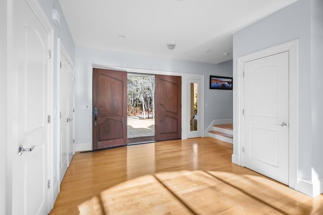 foyer with stairs, baseboards, and wood finished floors