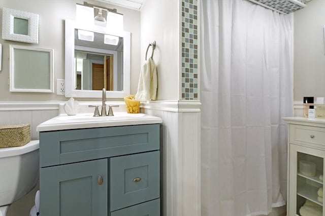 full bath with a wainscoted wall, vanity, a shower with shower curtain, and toilet