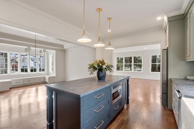 kitchen featuring stainless steel fridge, ornamental molding, built in microwave, and hanging light fixtures