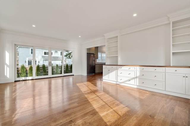 kitchen with stainless steel refrigerator, white cabinetry, ornamental molding, and hardwood / wood-style flooring