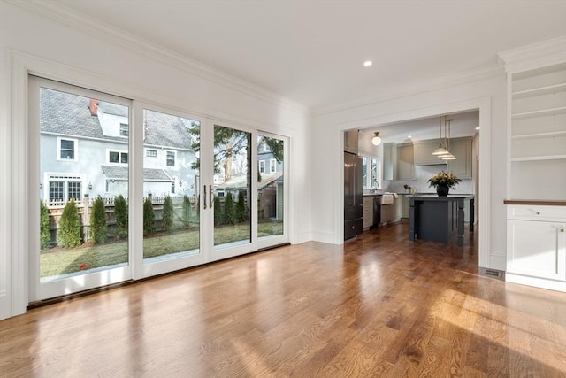 interior space with built in shelves, crown molding, and dark wood-type flooring