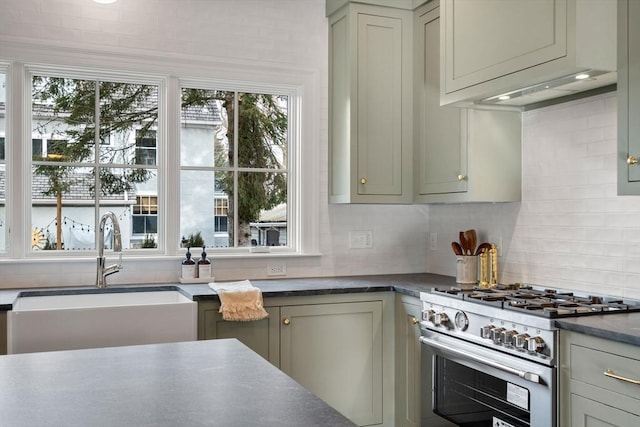 kitchen featuring sink, high end stainless steel range oven, decorative backsplash, gray cabinets, and range hood