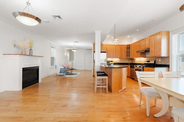 714 E 4th St Unit 3, Boston, MA 02127 - kitchen with gas stove, under cabinet range hood, light wood finished floors, backsplash, and crown molding