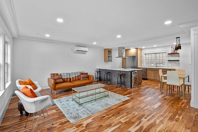 living room with a wall unit AC, crown molding, light hardwood / wood-style flooring, and beverage cooler