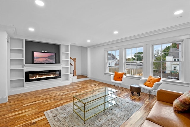 living room featuring hardwood / wood-style floors, built in features, and crown molding