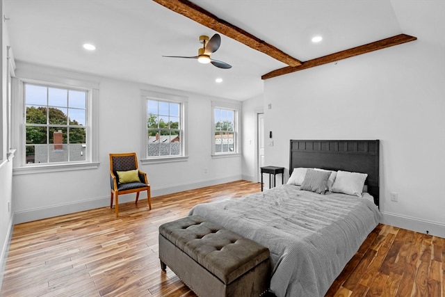 bedroom with multiple windows, ceiling fan, vaulted ceiling with beams, and light wood-type flooring