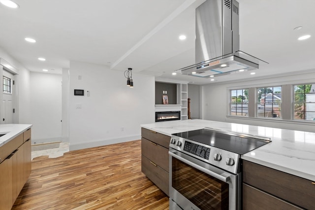 kitchen featuring electric range, light stone countertops, island range hood, and light wood-type flooring