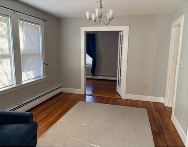 dining space featuring baseboard heating, a baseboard radiator, a chandelier, and wood finished floors