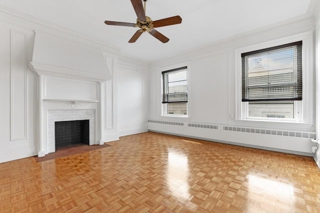 unfurnished living room featuring ornamental molding, a brick fireplace, radiator, and a decorative wall