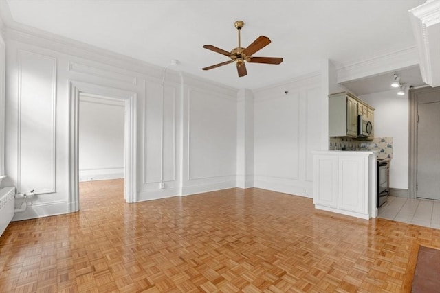 unfurnished living room with crown molding, a decorative wall, and a ceiling fan