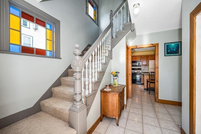 staircase featuring plenty of natural light, baseboards, and tile patterned floors