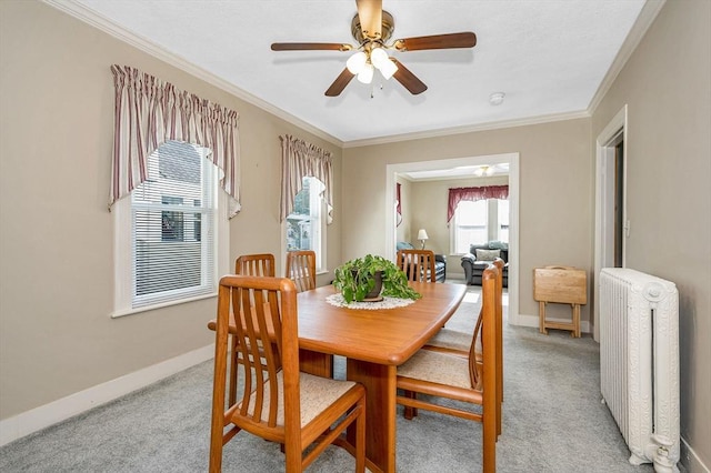 dining area with radiator, light colored carpet, a ceiling fan, ornamental molding, and baseboards