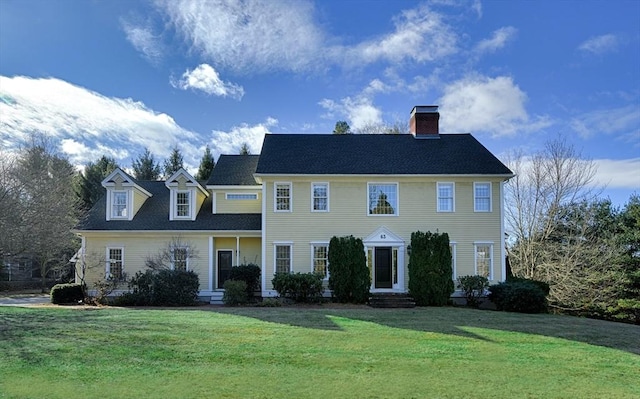 colonial house with entry steps, a chimney, and a front lawn