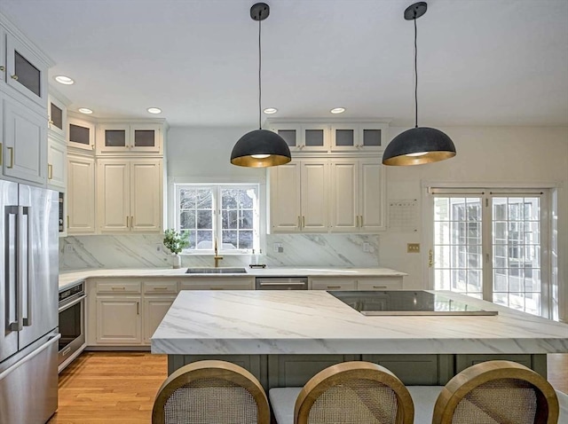 kitchen featuring decorative light fixtures, stainless steel appliances, glass insert cabinets, a healthy amount of sunlight, and a kitchen island