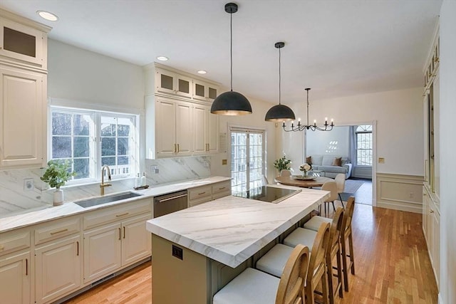 kitchen with dishwasher, a kitchen island, glass insert cabinets, a breakfast bar, and a sink