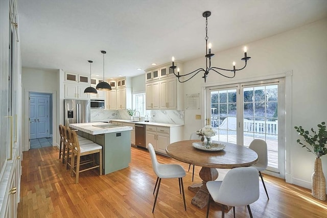 kitchen with glass insert cabinets, a center island, stainless steel appliances, light countertops, and pendant lighting