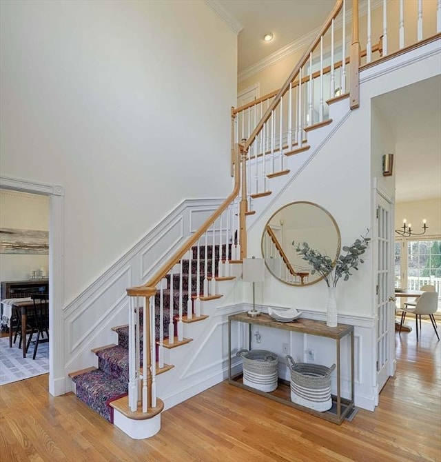 stairs featuring a notable chandelier, a decorative wall, and wood finished floors