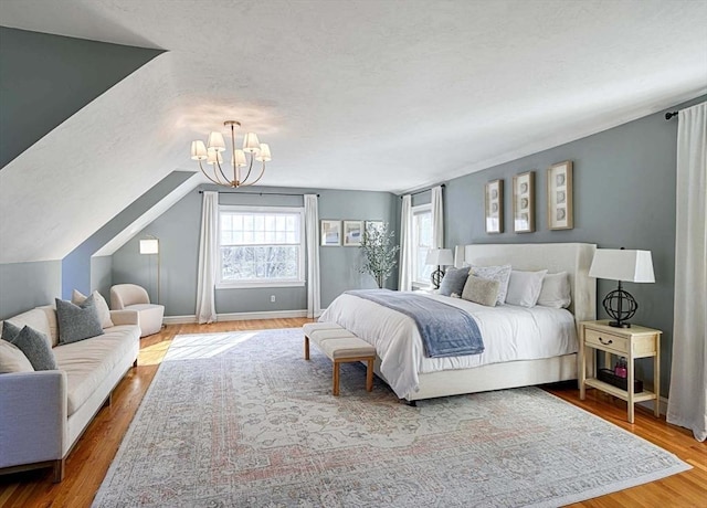 bedroom featuring lofted ceiling, a textured ceiling, wood finished floors, a chandelier, and baseboards