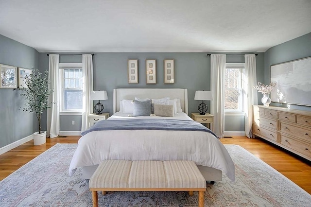 bedroom featuring multiple windows, light wood-style flooring, and baseboards