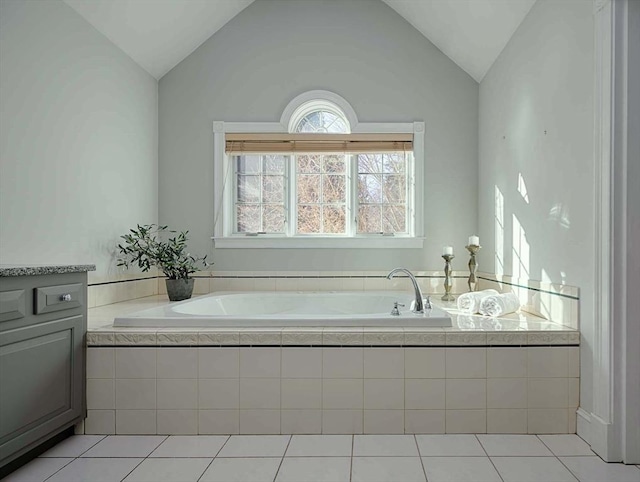 bathroom with a garden tub, tile patterned flooring, vaulted ceiling, and vanity