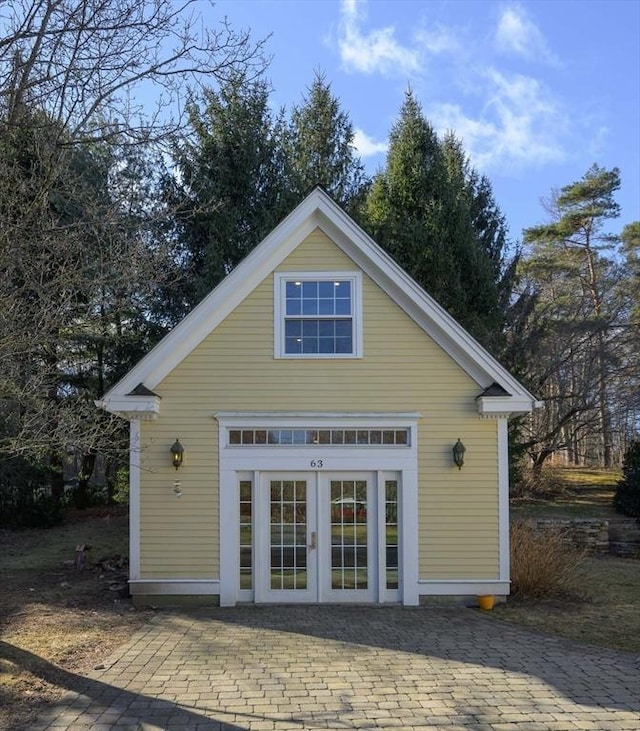 rear view of property featuring a patio area, an outdoor structure, and french doors