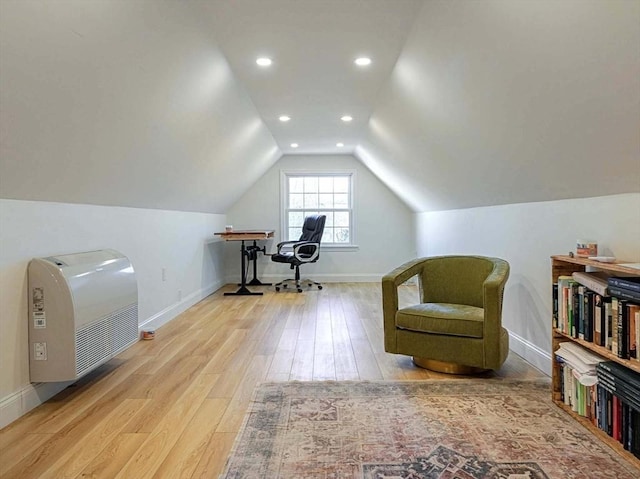 office area with light wood-style floors, baseboards, vaulted ceiling, and heating unit