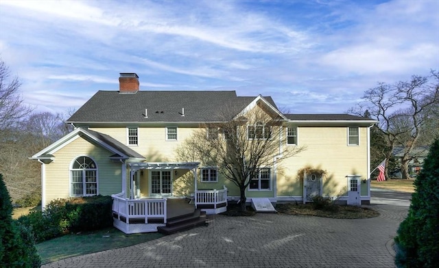 rear view of property with central air condition unit, a chimney, a wooden deck, and a pergola