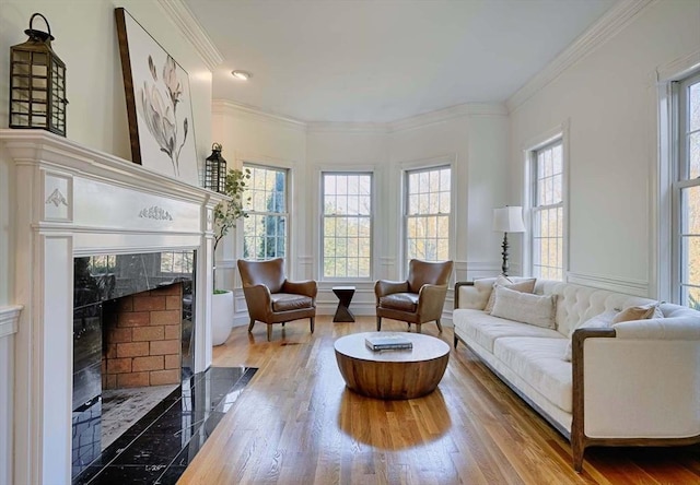 living room with plenty of natural light, a high end fireplace, crown molding, and wood finished floors