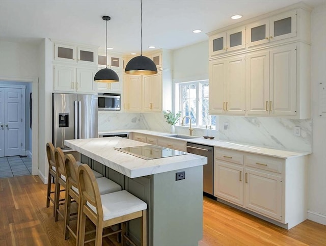 kitchen with appliances with stainless steel finishes, a center island, light countertops, and glass insert cabinets