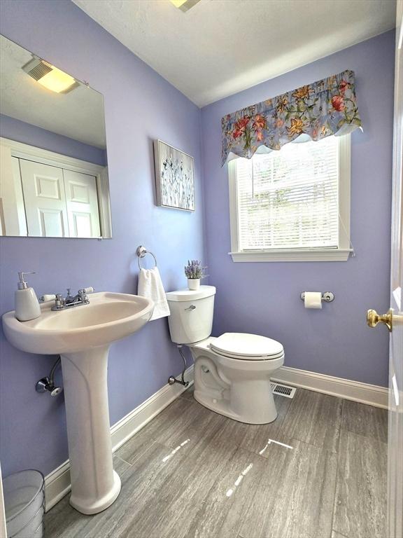 bathroom featuring wood finished floors, toilet, visible vents, and baseboards