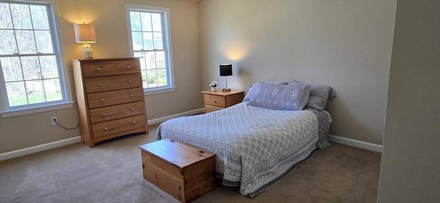 bedroom featuring multiple windows, light carpet, and baseboards