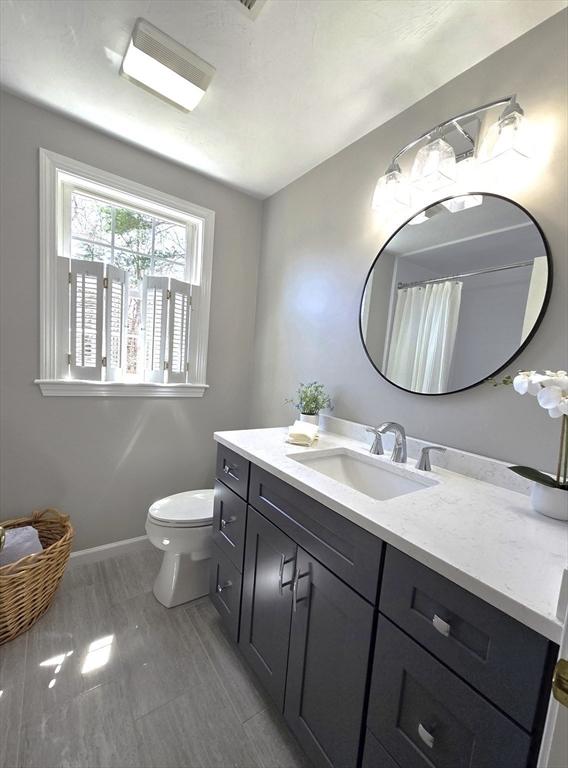 bathroom featuring vanity, toilet, and baseboards