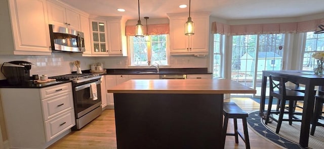 kitchen featuring white cabinets, backsplash, appliances with stainless steel finishes, and a sink