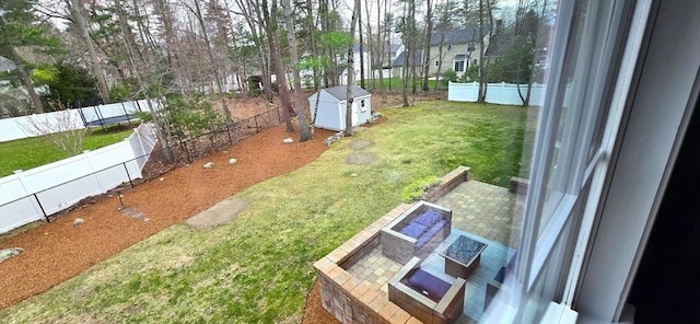 view of yard featuring a storage unit, a fenced backyard, and an outdoor structure