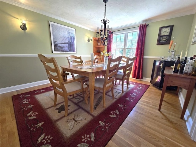 dining space with crown molding, a notable chandelier, wood finished floors, and baseboards