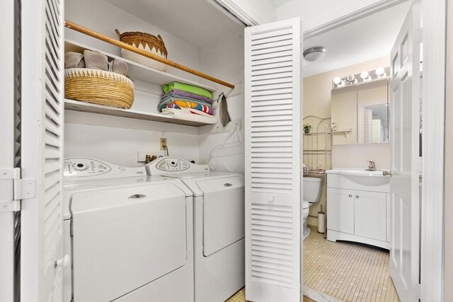 laundry area with laundry area, a sink, light tile patterned flooring, and separate washer and dryer